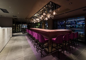 A bar area with a long counter, purple bar stools, hanging spherical light fixtures, and a view of the city through large windows. - The Skm Tokyo Hotel Dining (Tokyo)