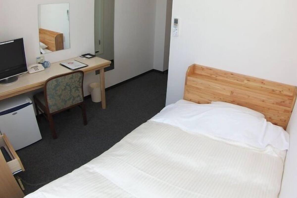 Une chambre d’hôtel avec un lit, un bureau, une chaise et un miroir.