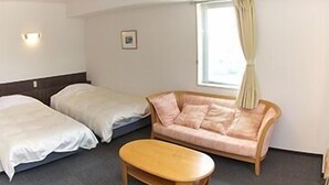 Camera d'albergo con due letti, un divano e un tavolino.