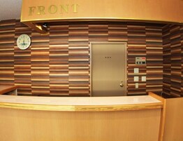 Zona de recepción con un cartel que dice 'FRONT', un reloj y un ascensor.