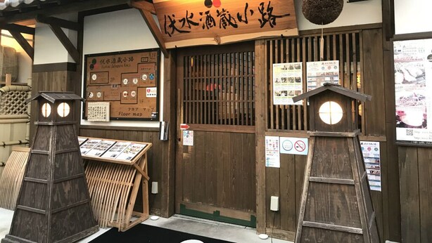 Un établissement japonais traditionnel, caractérisé par son architecture en bois, une enseigne et un plan des lieux affiché.