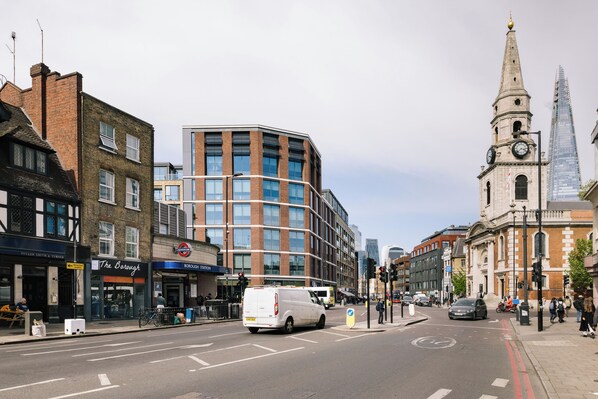 A street view with a white van, a bus, and a historic building with a clock tower. - Borough High Street Rooms (London)