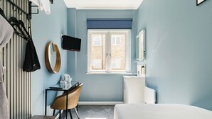 A hotel room with a bed, a desk with a chair, a television, a window, and a bathroom.