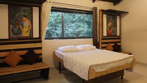 A room with a bed, a bench, and two paintings.