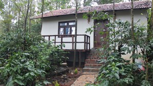 A rustic building with a tiled roof, a wooden balcony, and a brick staircase leading to a door.