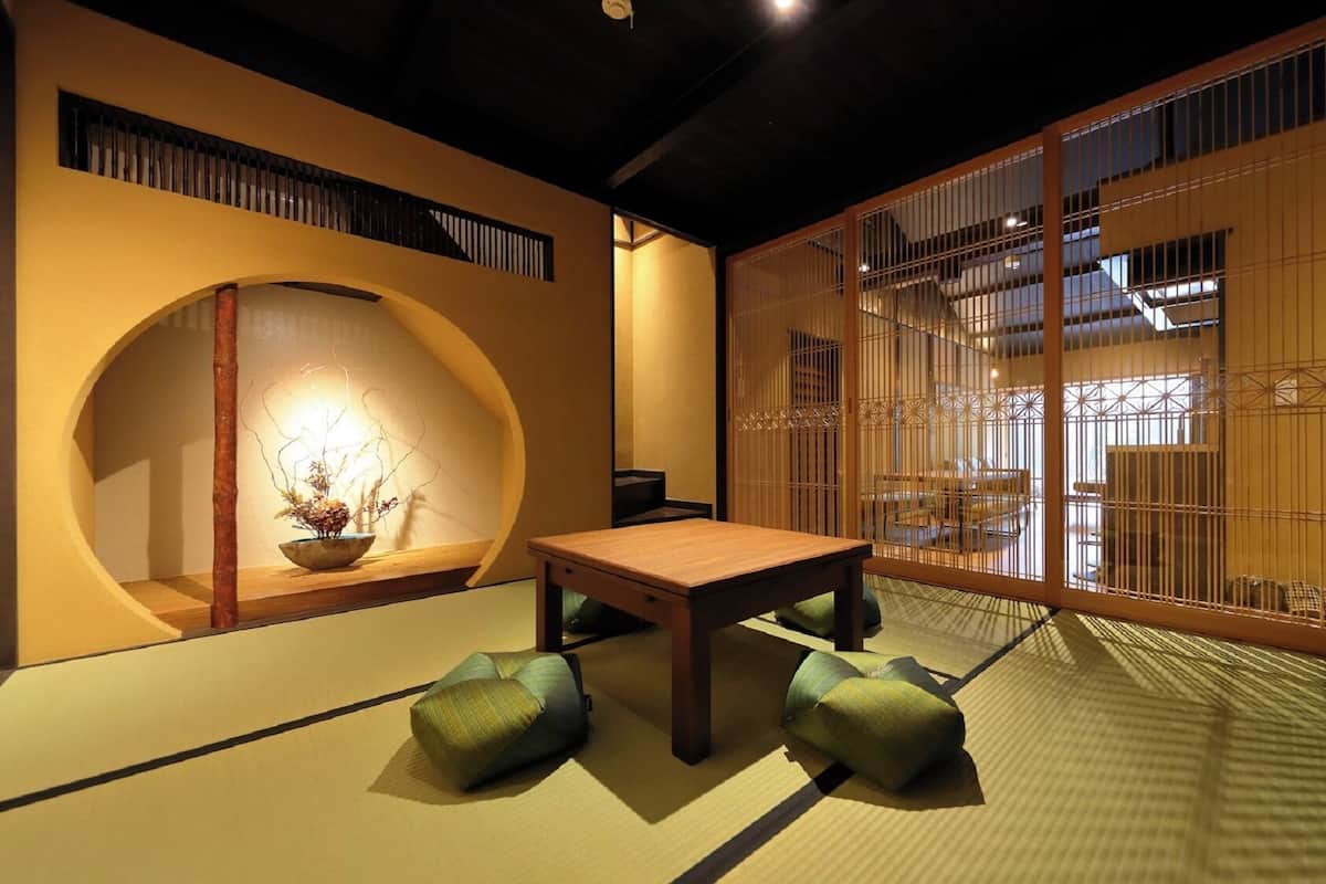 A traditional Japanese room with tatami flooring, a low table, cushions, and a shoji screen.