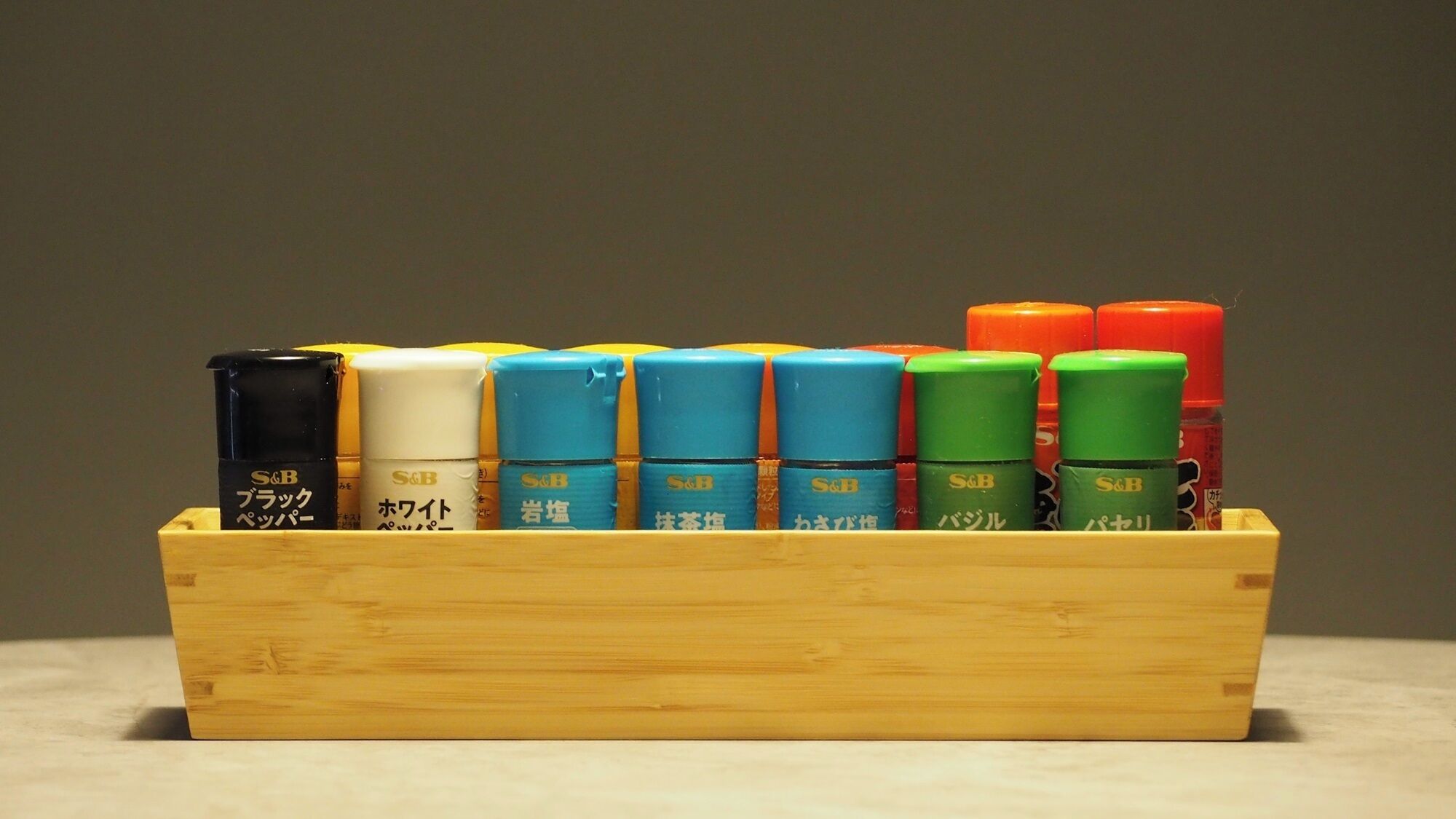 A wooden box containing various colored containers with Japanese text.
