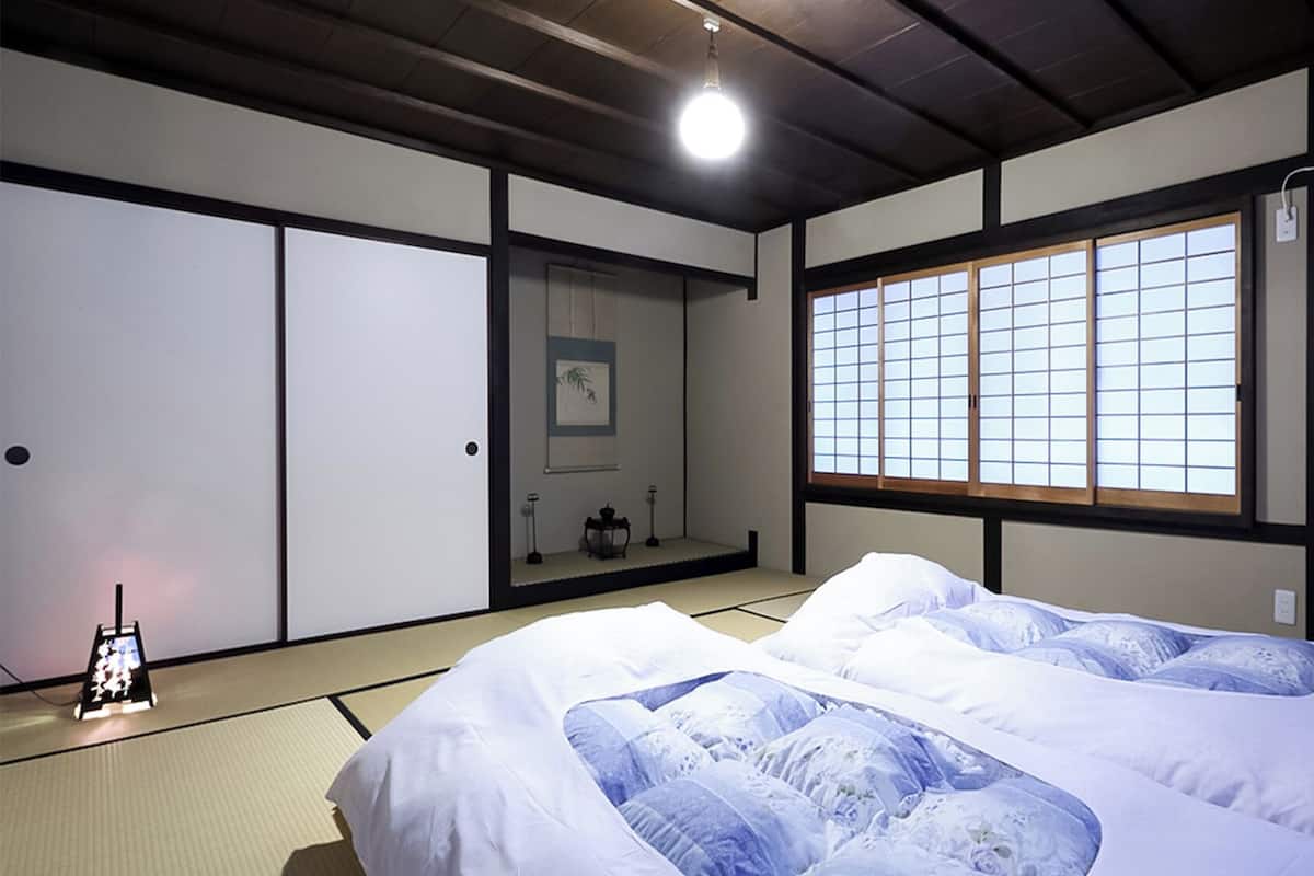 Perinteinen japanilaistyylinen huone, jossa on tatamimatto, futon-patja, liukuovet ja shoji-paperi-ikkuna.