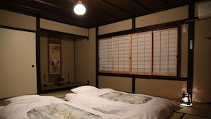 A traditional Japanese room with tatami flooring, a shoji screen, and two beds with futon mattresses. - Kyomachiya Oyado Hana (Kyoto)