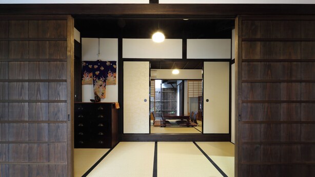 A traditional Japanese room with tatami flooring, sliding doors, and a hanging artwork. - Kyomachiya Oyado Hana (Kyoto)