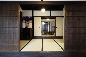 Una stanza tradizionale giapponese con pavimento in tatami, porte scorrevoli e un'opera d'arte appesa al muro.