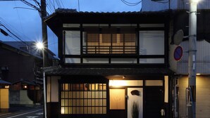A traditional Japanese building with a two-story structure, a sliding door, and a small entrance area. - Kyomachiya Oyado Hana (Kyoto)