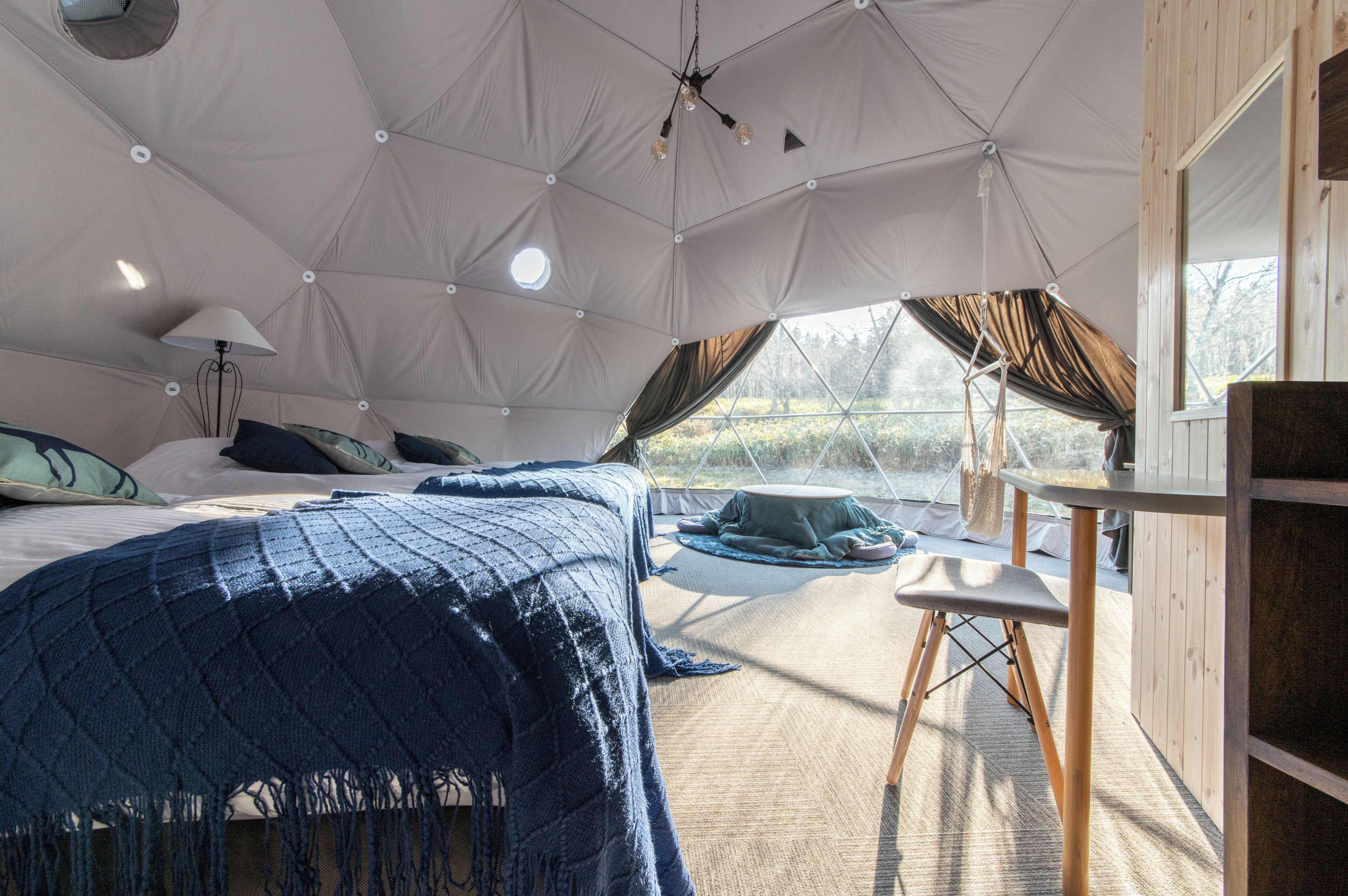 Habitación tipo tienda de campaña con una cama, una mesa y una silla.