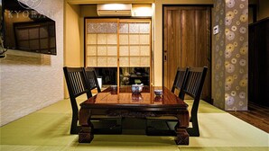 A traditional Japanese dining room with tatami mats, a low wooden table, and black chairs. - Kyorana Kyogetsutei (Kyoto)