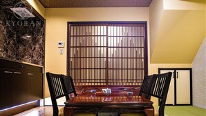 A traditional Japanese-style room with tatami flooring, a low wooden table, and a sliding door with vertical bars. - Kyorana Kyogetsutei (Kyoto)