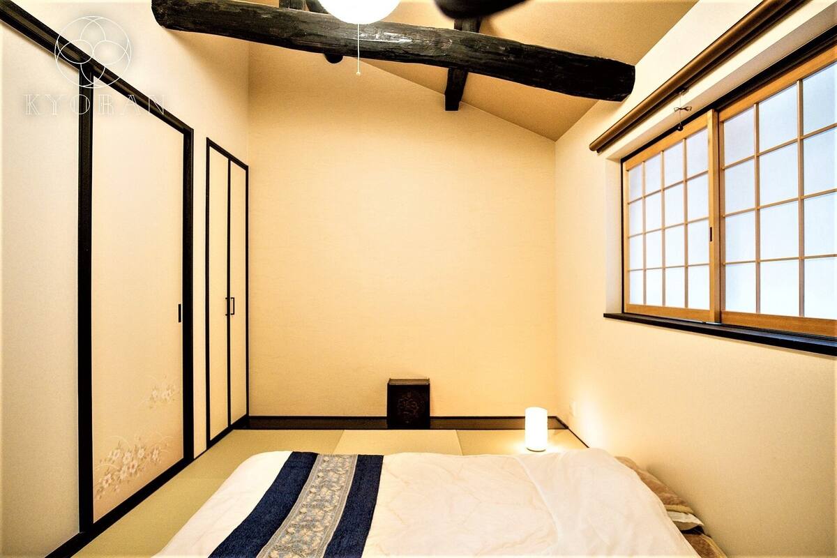 Una habitación tradicional japonesa con suelo de tatami, techo bajo y puerta corredera.