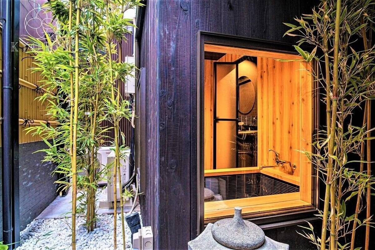 Una habitación tradicional japonesa con fachada de madera, puertas correderas y un farolillo de piedra.