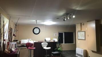 Una habitación con un escritorio, dos sillas, un reloj, un radiador y una ventana.