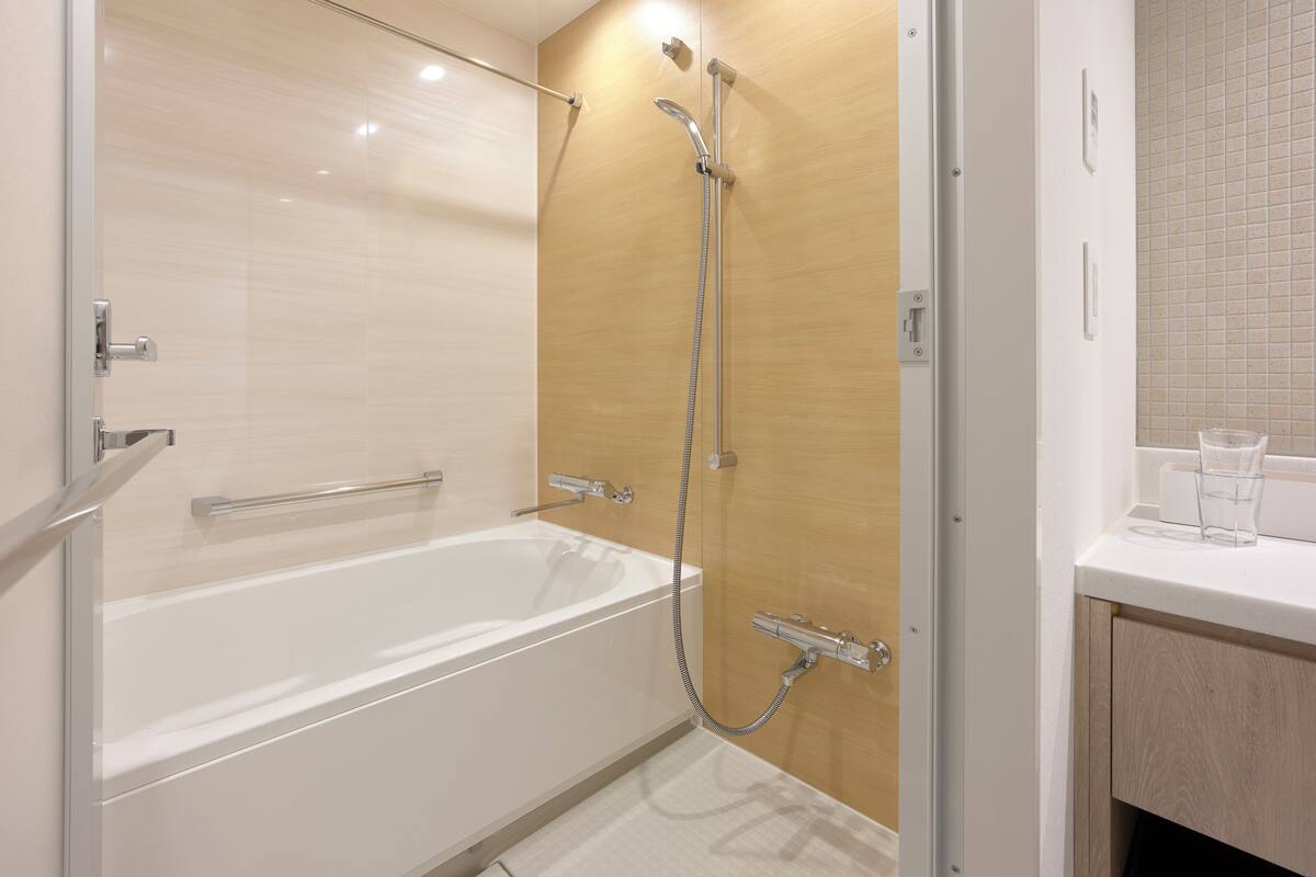 A modern bathroom with a glass-enclosed shower, a white bathtub, and a wooden vanity with a mirror.