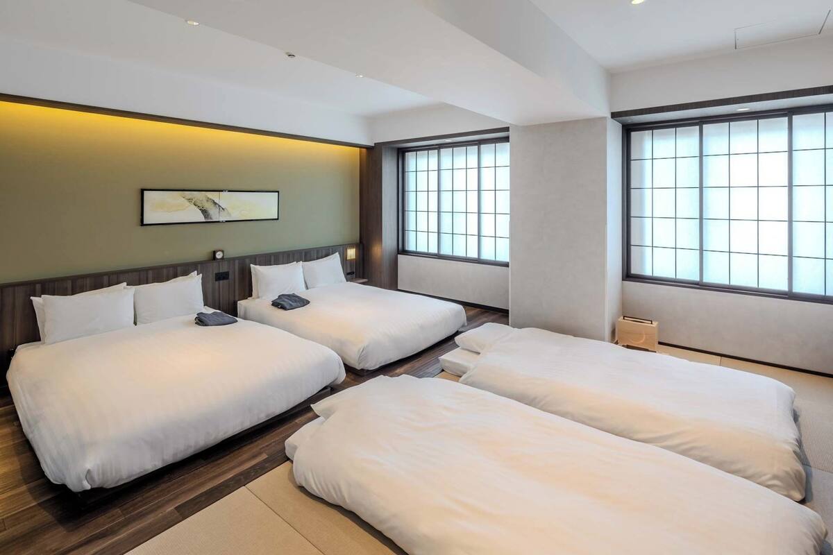 A hotel room with two beds, a large window, and a wall-mounted artwork.