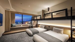 Ett hotellrum med våningssängar, utsikt över staden, en soffa och en stege.