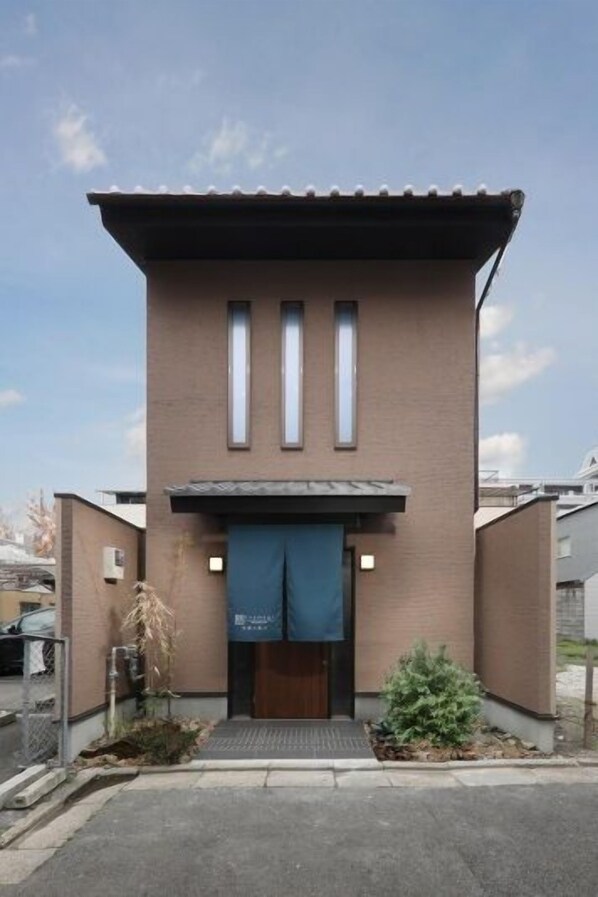 Un bâtiment doté d’un toit plat, de trois fenêtres verticales et d’un auvent bleu.