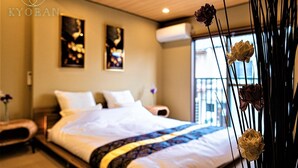 Una habitación de hotel con cama, mesita de noche y ventana con vistas.