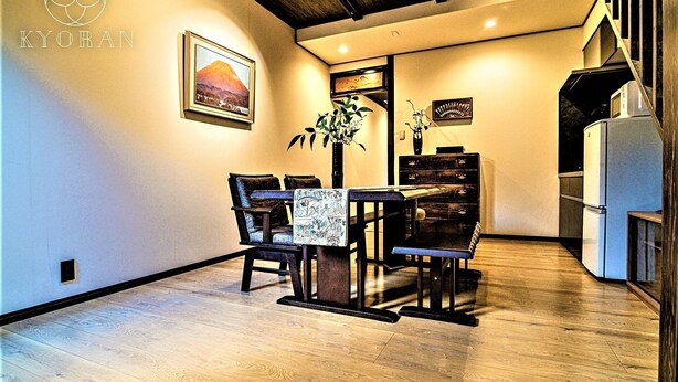 Un comedor con una mesa y sillas de madera, un jarrón con una planta y un cuadro con una imagen de una montaña.