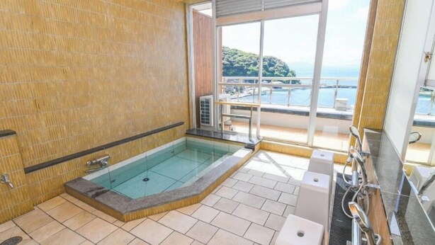Un baño con jacuzzi de vidrio, suelo de baldosas y vistas a un balcón con piscina.