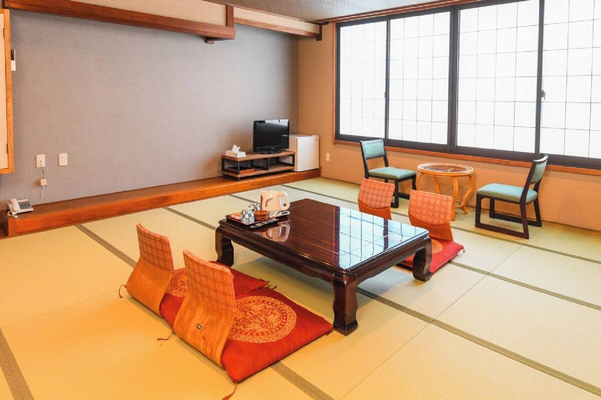 A traditional Japanese-style room with tatami flooring, a low wooden table, and a television.