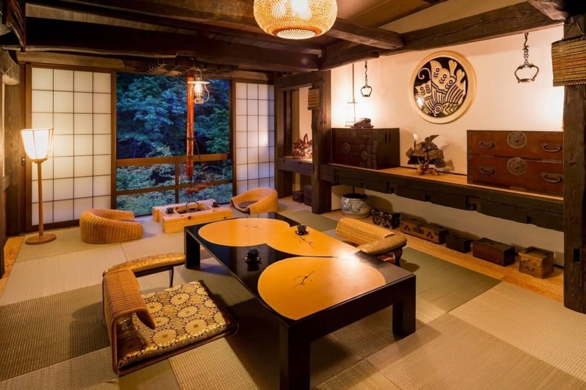 Um quarto japonês tradicional com tatames, mesinhas baixas e uma porta deslizante para um jardim.