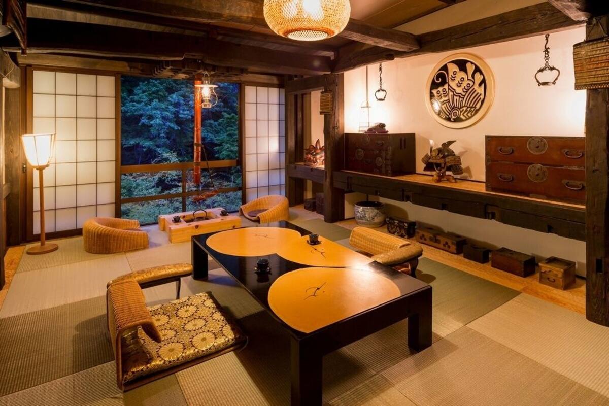 A traditional Japanese room with tatami flooring, low tables, and a sliding door leading to a garden.