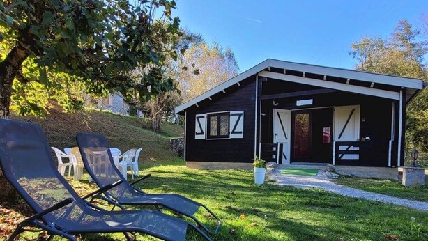 A modern house with a covered porch, a lawn with chairs, and a clear sky.