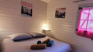 A room with a bed, pillows, a nightstand with a lamp, and two posters on the wall. - "Calamès" Chalet de Montorgueil (Saurat)