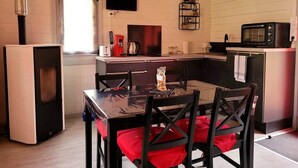 A compact kitchen with a dining table, chairs, a TV, and a microwave.