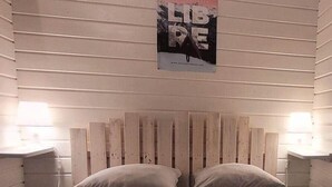 A bed with a wooden headboard, two pillows, and three rolled towels. - "Sédour" Chalet de Montorgueil (Saurat)