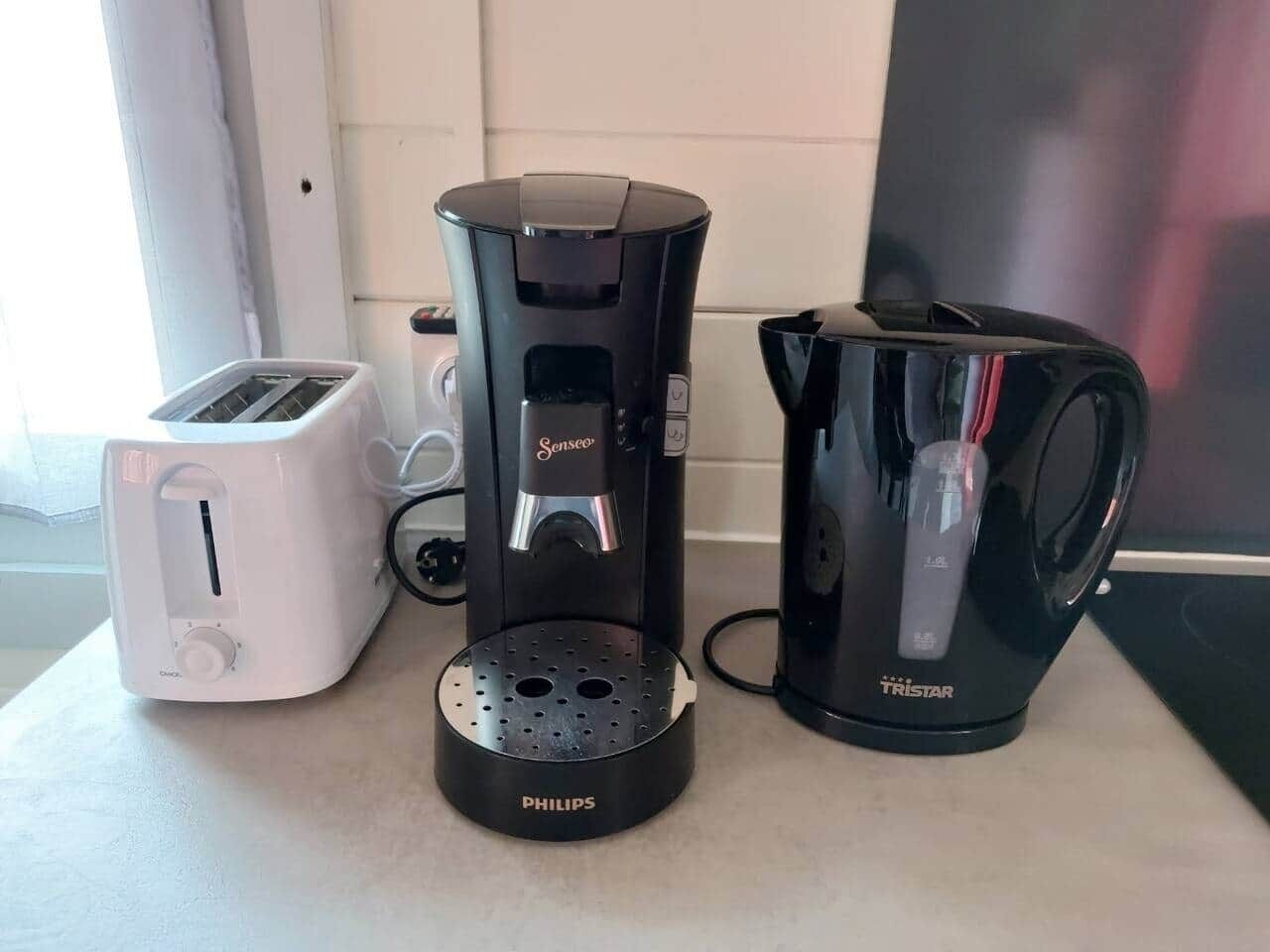 Une cuisine équipée d’une machine à café Philips, d’une machine à café Senseo et d’une cafetière Tristar.