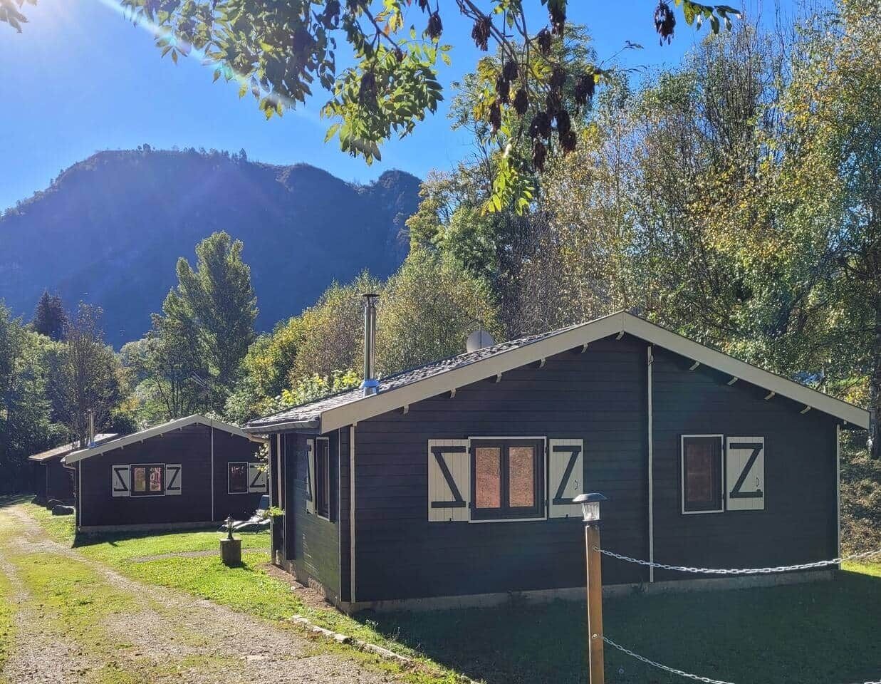 Deux cabanes avec une vue sur les montagnes, une zone herbeuse et une clôture en treillis métallique.