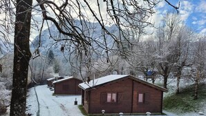 A row of wooden cabins with snow-covered roofs, surrounded by trees and mountains. - "Sédour" Chalet de Montorgueil (Saurat)