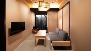 Una sala de estar moderna con un televisor de pantalla plana, un sofá, una mesa y un puerta corredera que da a un balcón.