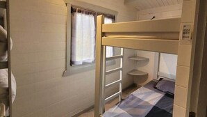 A bunk bed room with a window, a ladder, and a small shelf.