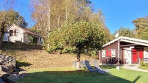 A property with a stone structure, a tree, and a building with a red door. - "3 Seigneurs" Chalet de Montorgueil (Saurat)