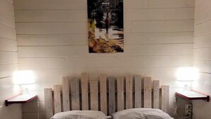 A room with a wooden headboard, two bedside tables, and a poster on the wall. - "3 Seigneurs" Chalet de Montorgueil (Saurat)
