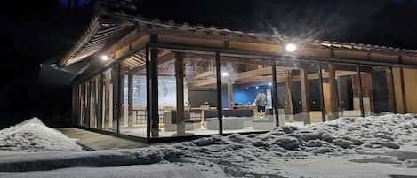 A modern glass building with a wooden roof, surrounded by snow.