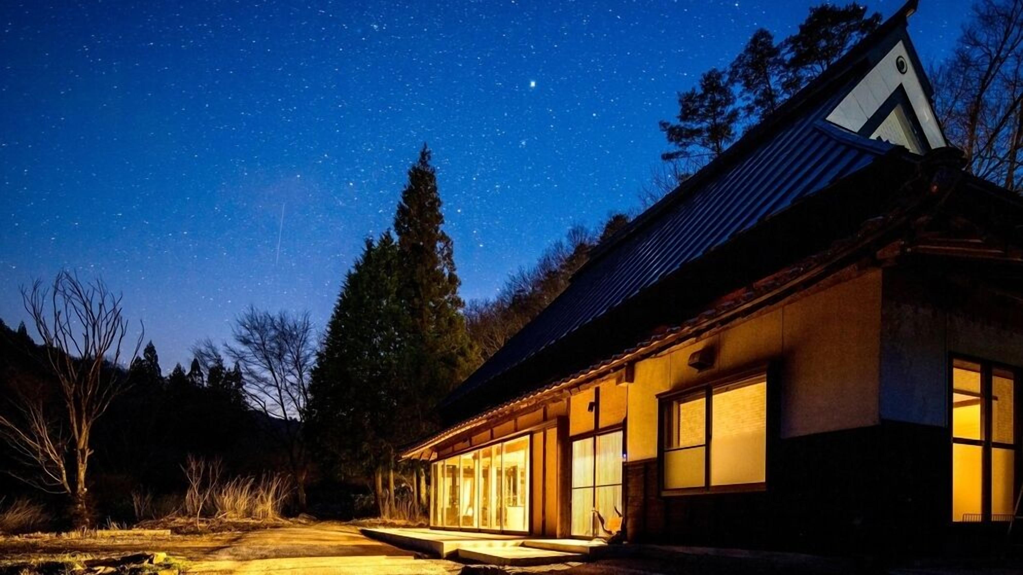 A house with a large window, a visible door, and a starry night sky.