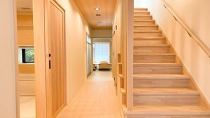 A wooden staircase leading to a room with a window, a door, and a small table with a chair.