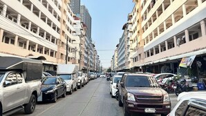 Un aparcamiento de varios pisos con vehículos estacionados a ambos lados, rodeado de edificios altos.