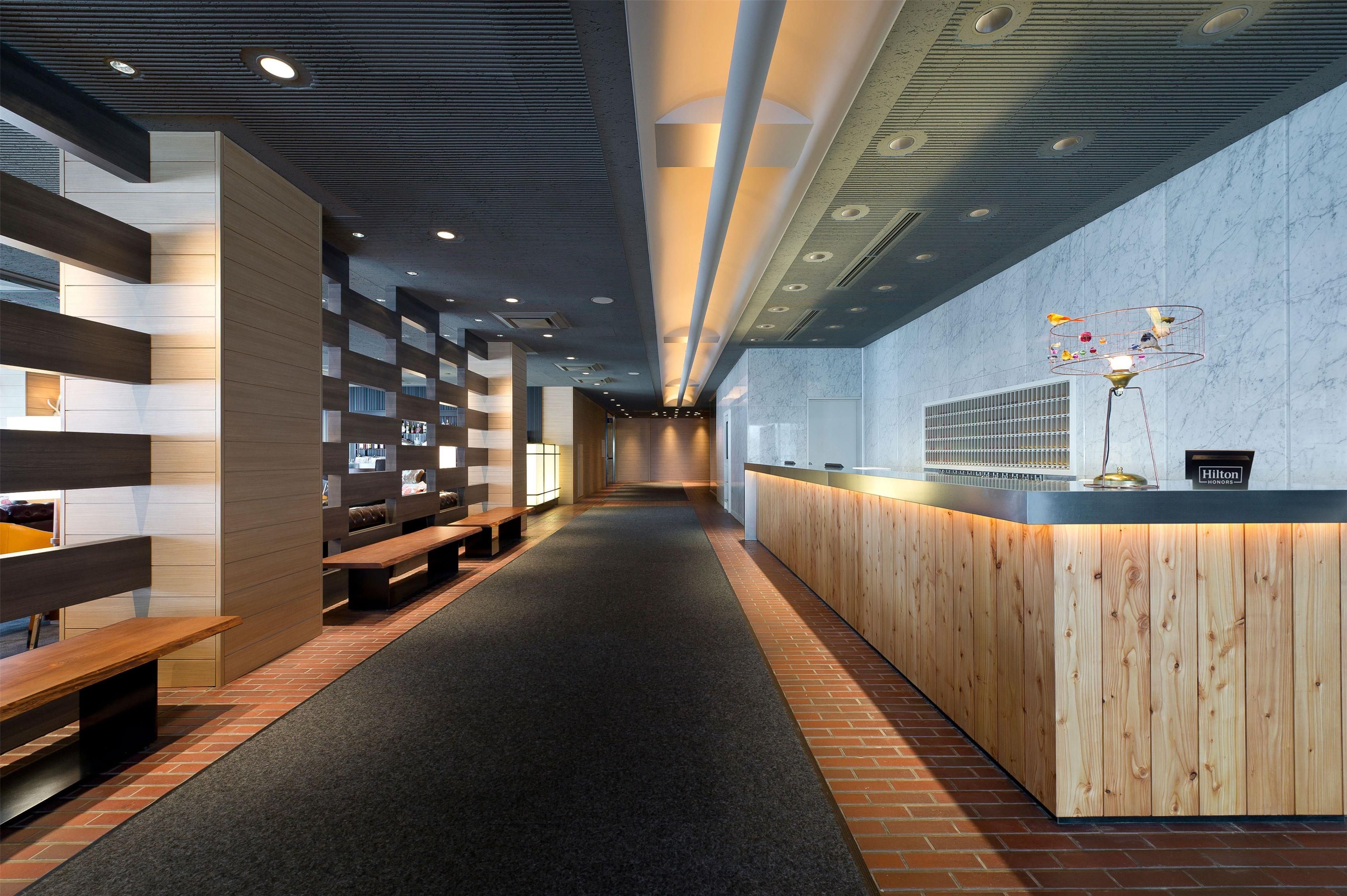 A hotel lobby with a reception desk, seating areas, and a corridor leading to other parts of the hotel.