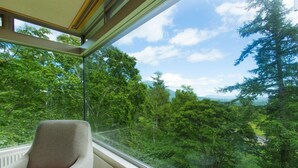 Una habitación con un ventanal que da a una zona boscosa.