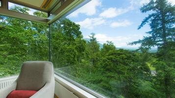 A room with a large window overlooking a forested area.